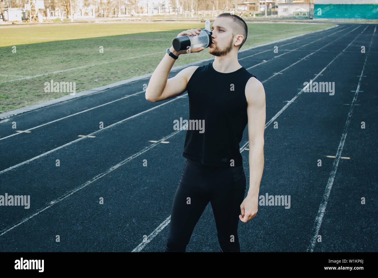Muscolare di esili uomo in formazione presso lo stadio bevande acqua da uno  sport shaker. ricreativo sport. athletic esercizio Foto stock - Alamy