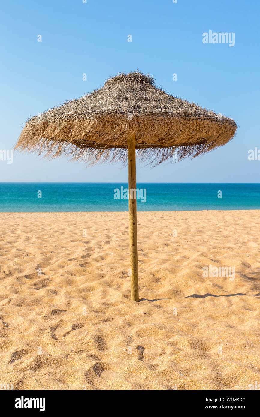 Uno di paglia ombrellone in spiaggia al mare blu in Portogallo Foto Stock