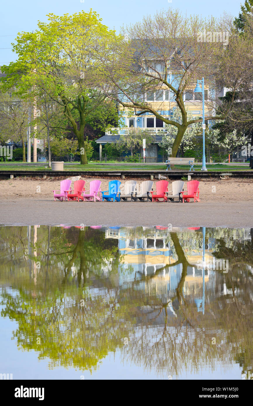Una fila di muskoka colorate sedie spiccano su un invaso Woodbine Beach. Foto Stock