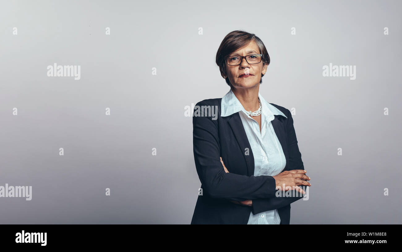 Senior donna imprenditore nel business formale usura. Senior imprenditrice isolato su sfondo grigio guardando la fotocamera. Foto Stock