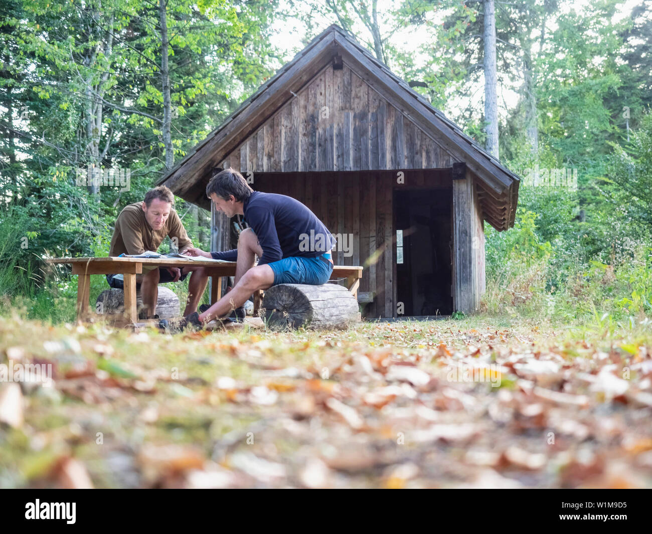 Due escursionisti maschio mappa di lettura durante i momenti di relax davanti al piccolo rifugio nella Foresta Nera, Baden-Württemerg, Germania Foto Stock