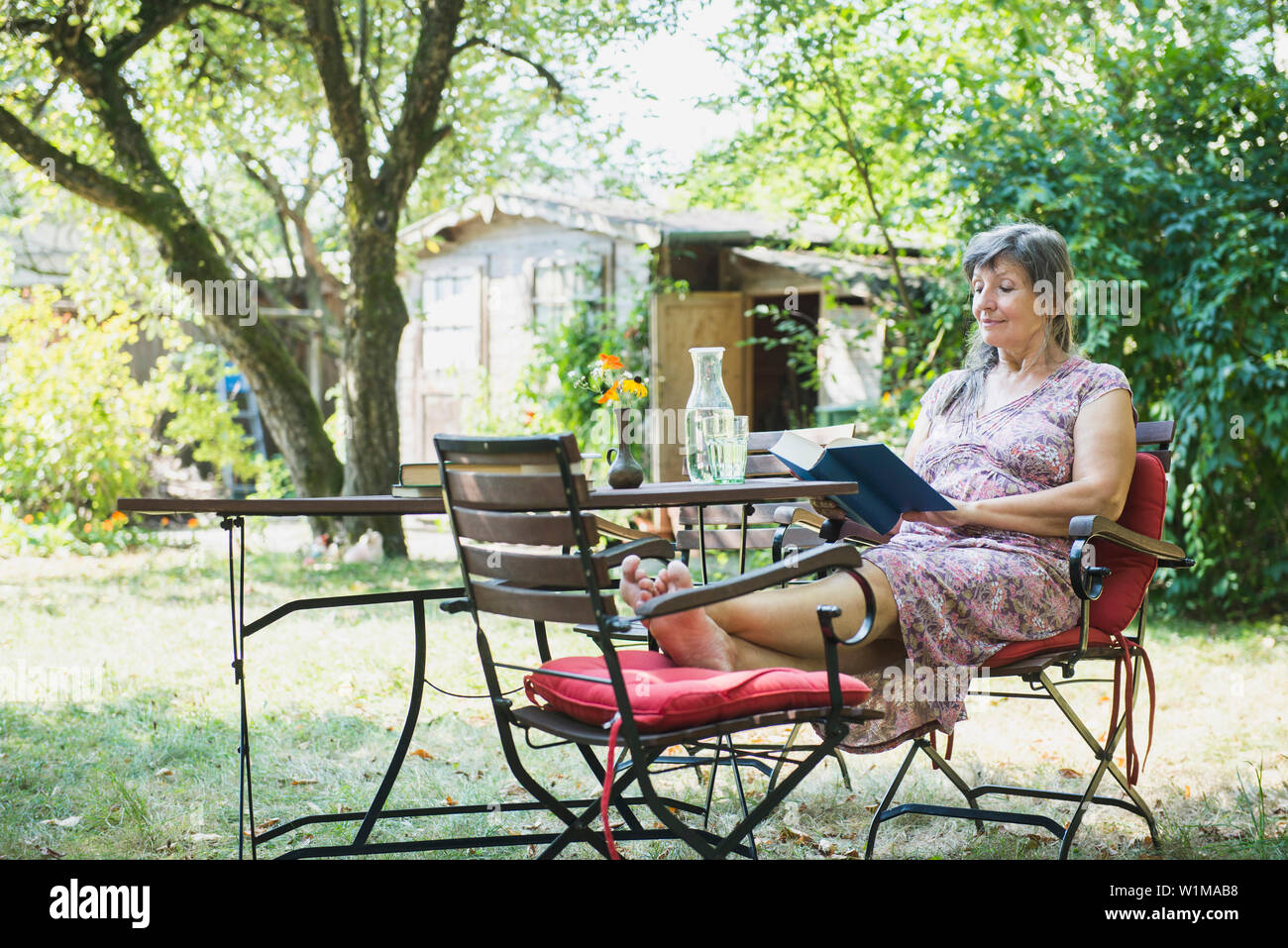 Senior donna leggendo un libro in giardino, Altötting in Baviera, Germania Foto Stock