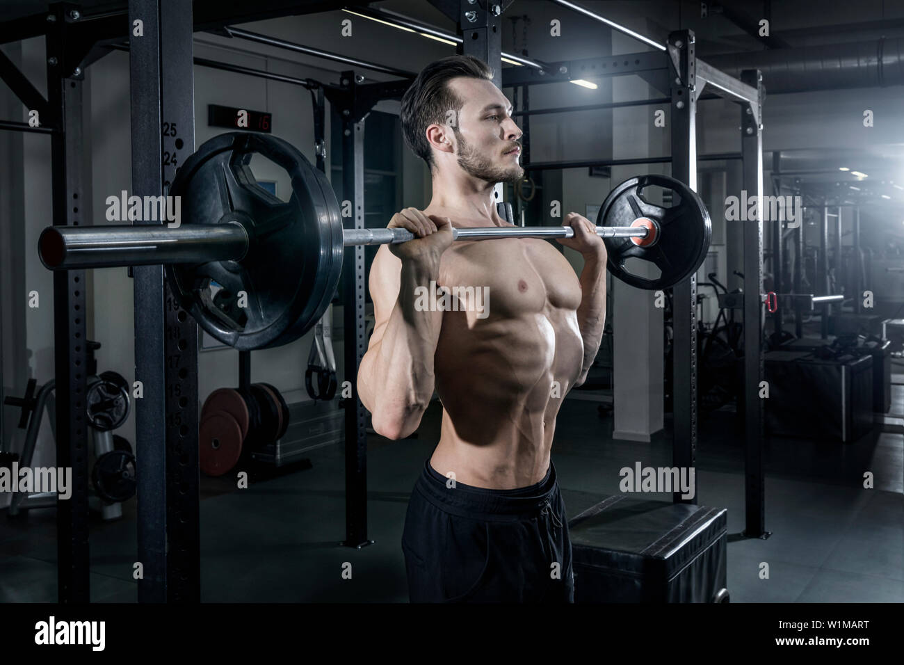 Shirtless uomo muscolare esercitando con barbell in palestra Foto Stock