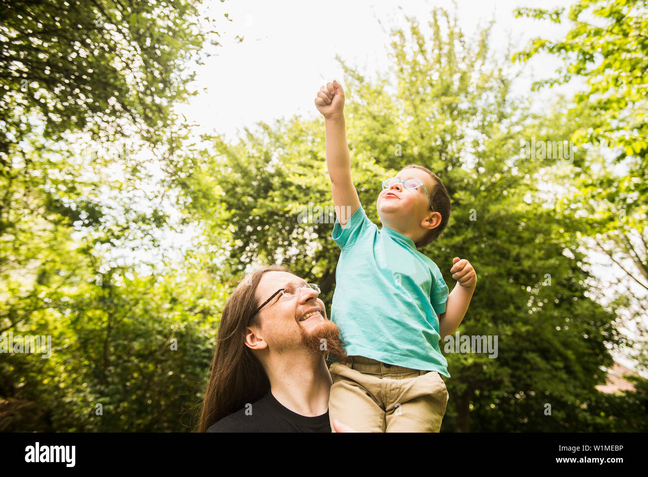 Padre con figlio agendo come supereroe in giardino Foto Stock