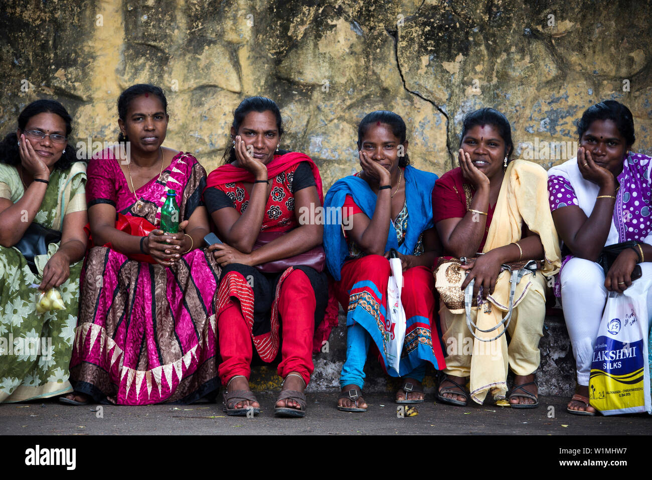 Sei donne locali seduti su una parete, Thiruvananthapuram Kerala, Indien Foto Stock