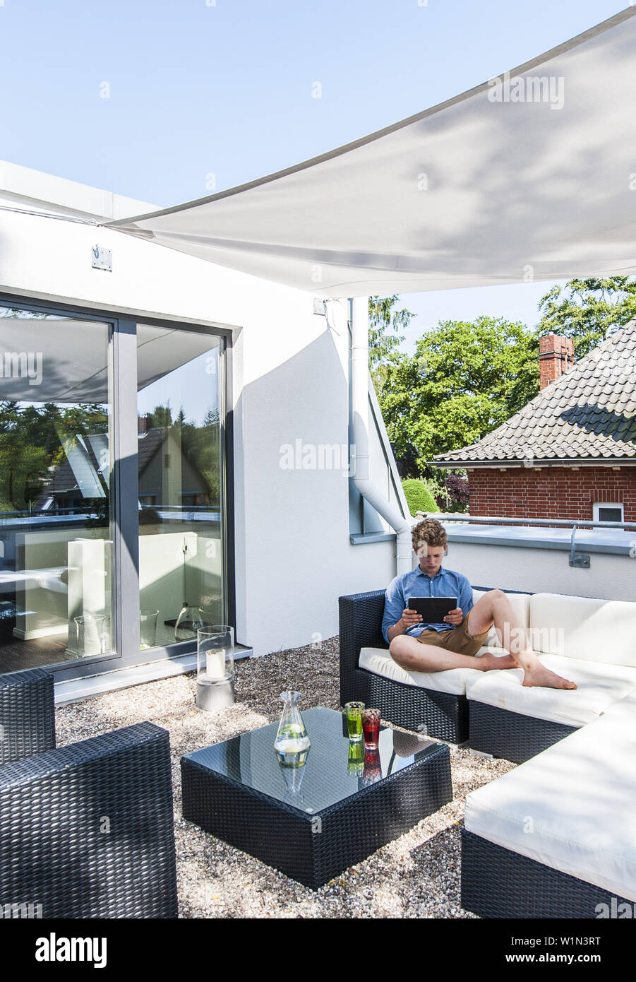 Giovane ragazzo con iPad sul tetto di un moderno a singola casa di famiglia a Amburgo, Germania settentrionale, Germania Foto Stock