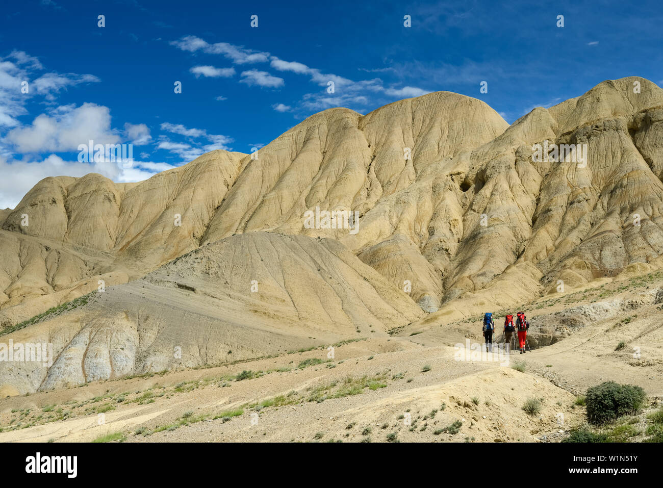 Tre escursionisti gli escursionisti in paesaggio surreale tipico per la Mustang in alto deserto intorno alla Kali Gandaki valley, la più profonda valle nel mondo Foto Stock