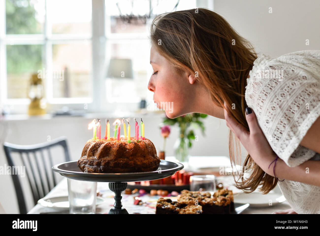 Ragazza adolescente soffiando le candeline sulla torta di compleanno a parte in Amburgo, Germania Foto Stock