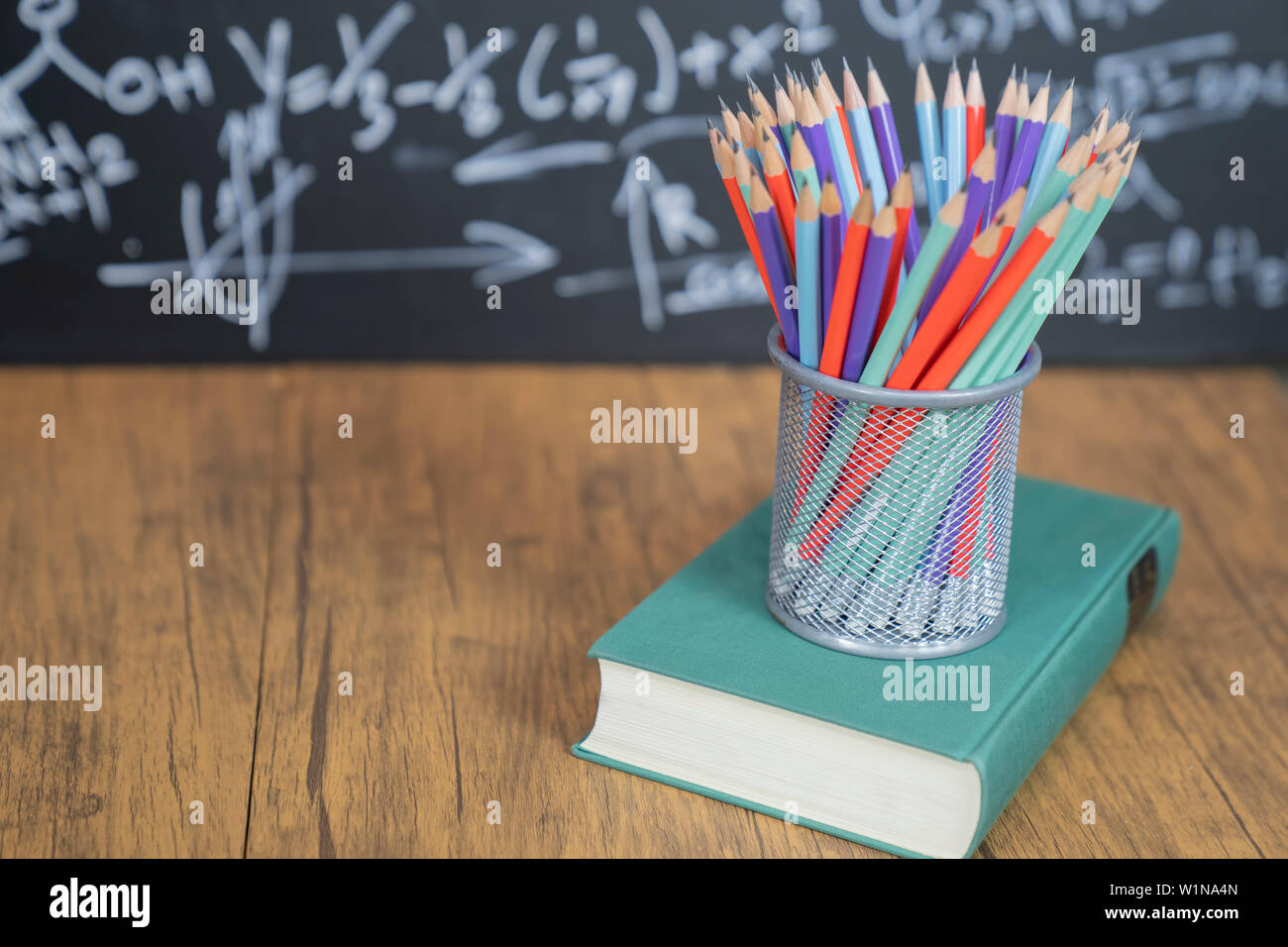 Molte matite nel cestello. Concetto di istruzione o ritorno a scuola su sfondo nero. Foto Stock