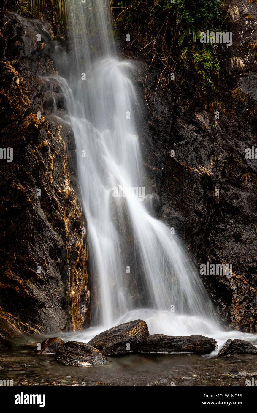 Una cascata sulla valle Walk, Ghiacciaio Franz Josef, Isola del Sud, Nuova Zelanda Foto Stock