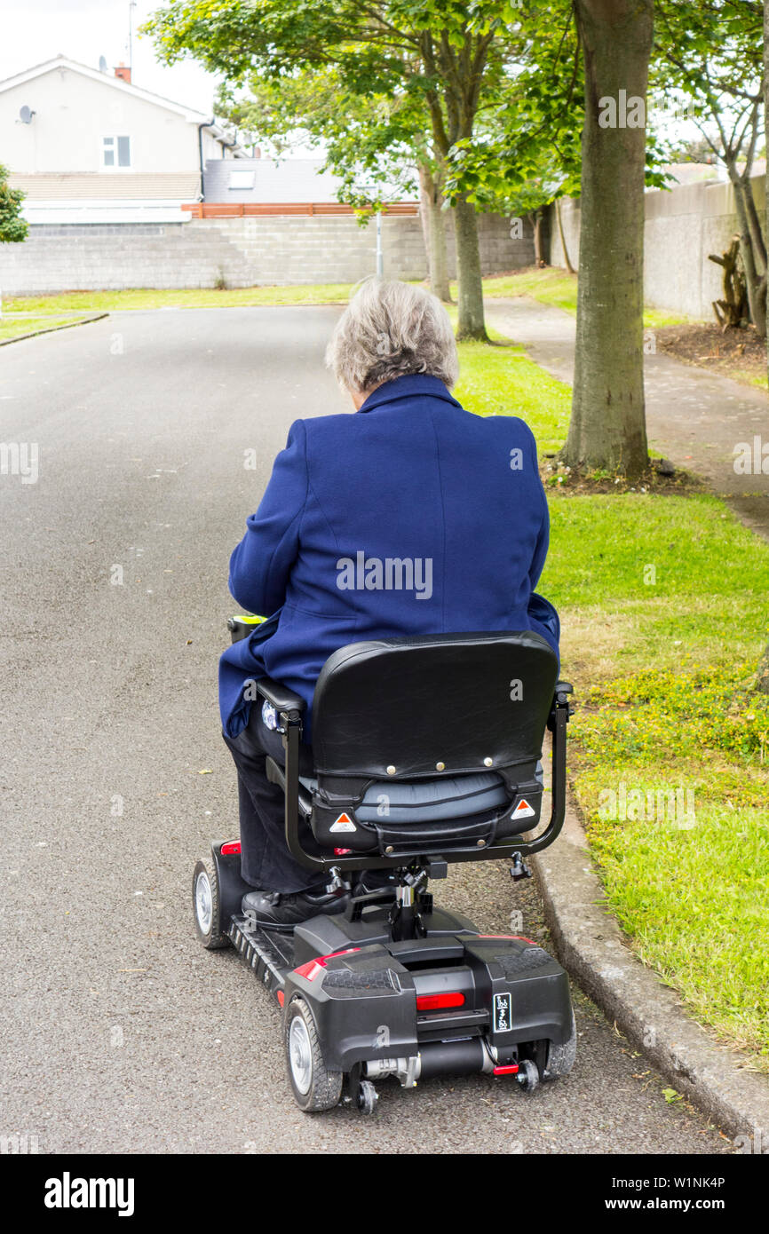 Una donna più anziana che viaggiano su una mobilità scooter Foto Stock