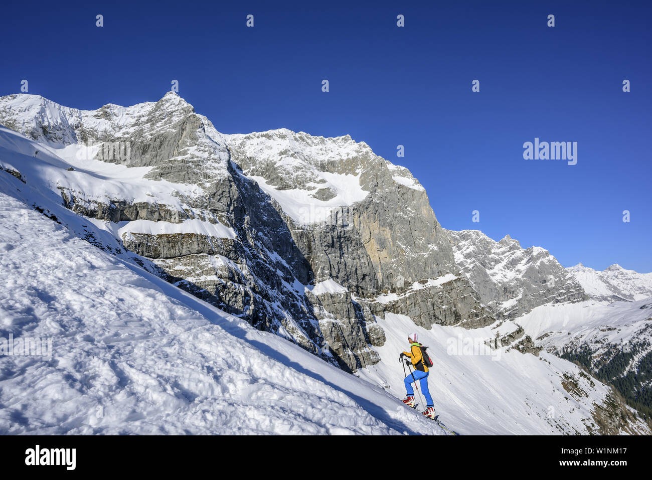 La donna torna per sci di fondo crescente a Hochglueckkar, Eiskarlspitze e Spritzkarspitze in background, Hochglueckkar, Eng, parco naturale Karwendel, Karw Foto Stock