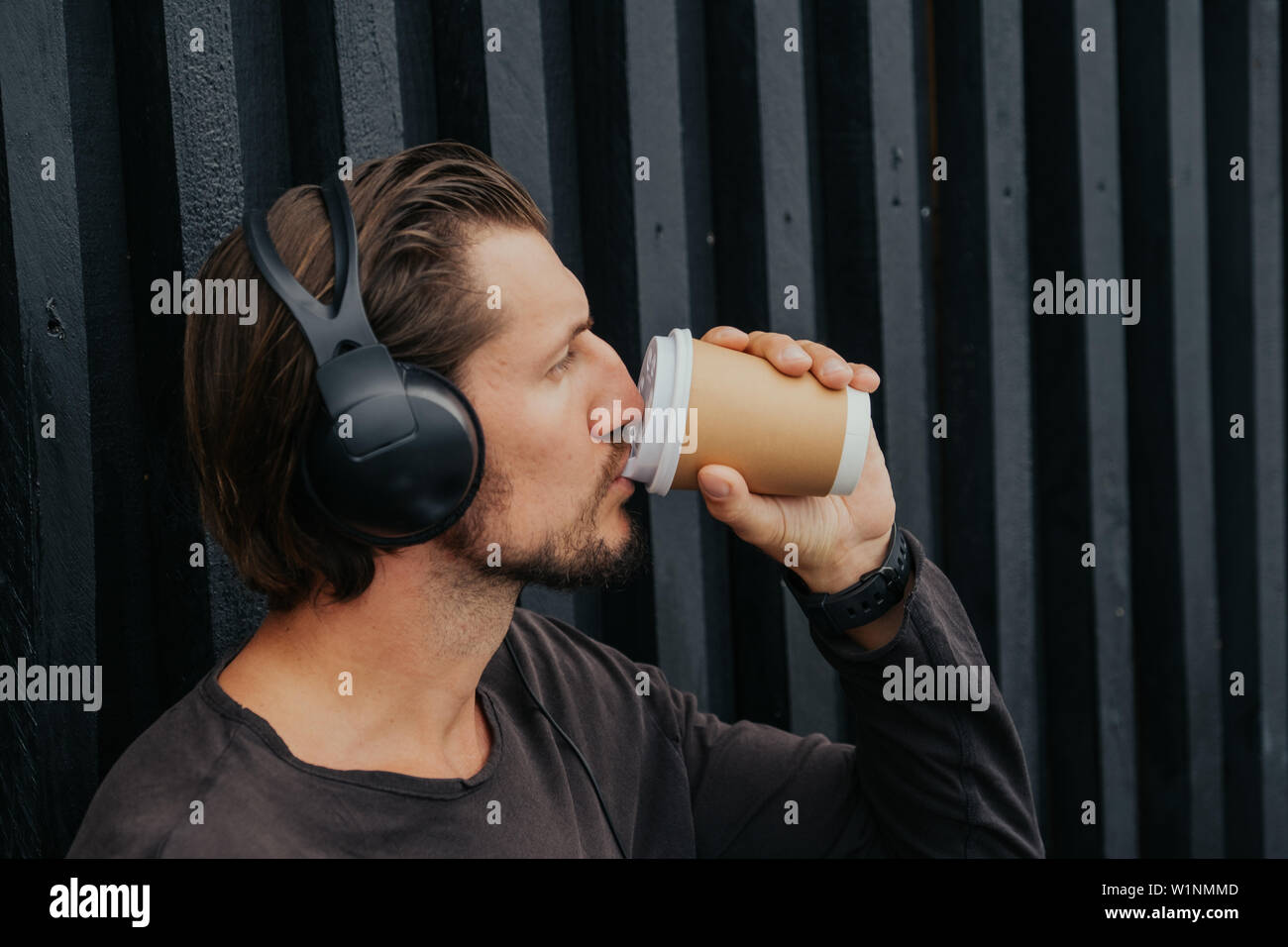 Fotografo freelance di localizzazione ho la città in montagna con il tè caldo o caffe ascolta musica in cuffia, zainetto e lavora su un notebook Foto Stock