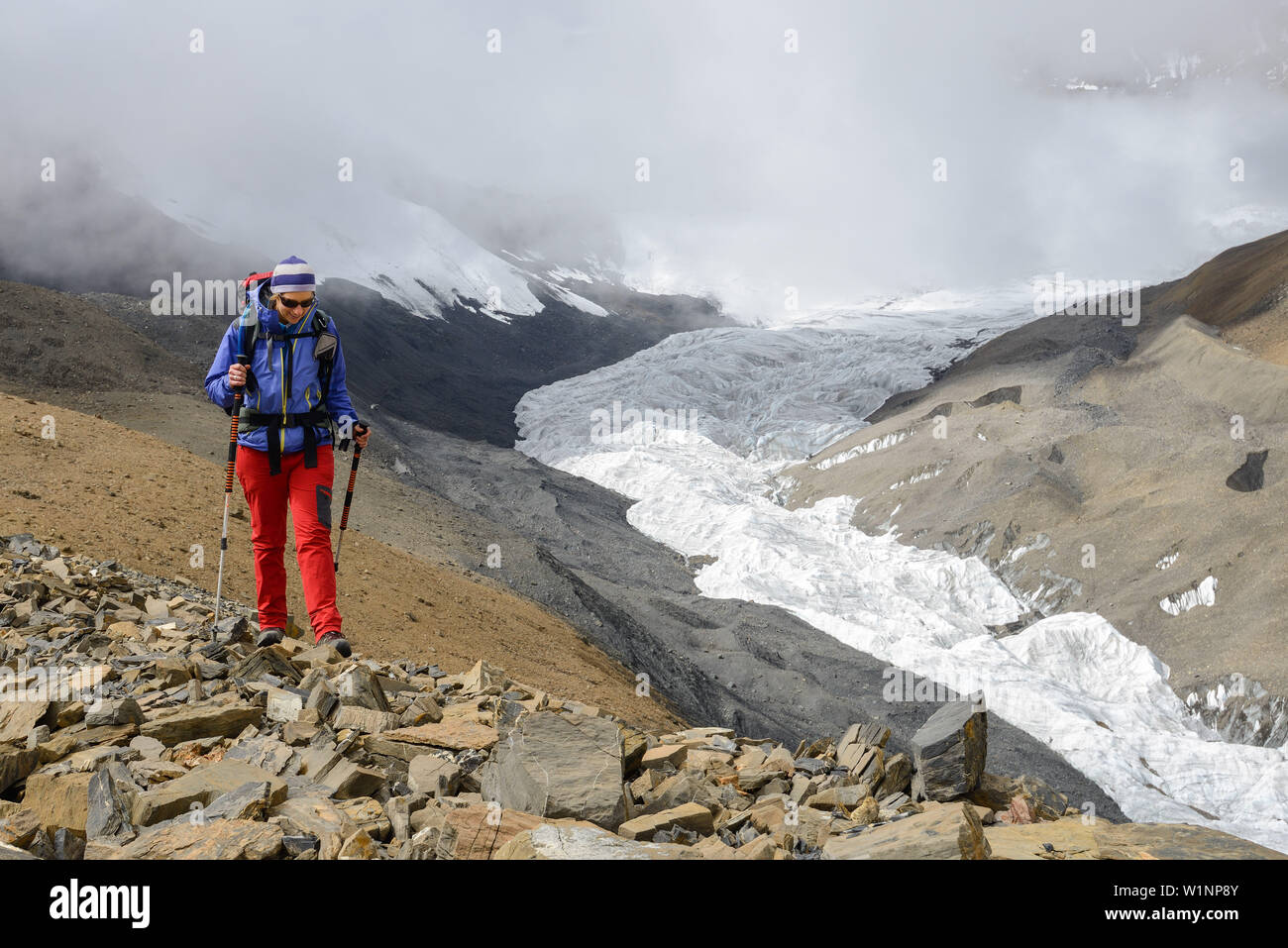 Giovane donna trekker escursionismo nel fronte del ghiacciaio di Purbung Himal (6500 m) sul suo modo da Nar su Teri Tal a Mustang, Nepal, Himalaya, Asia Foto Stock