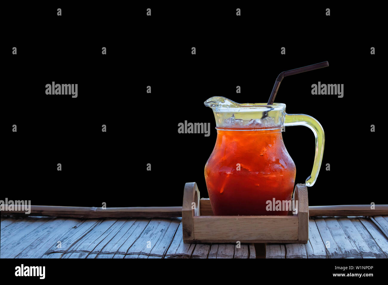 Tè freddo in un vasetto di vetro sul bambù flooringon uno sfondo nero. Foto Stock