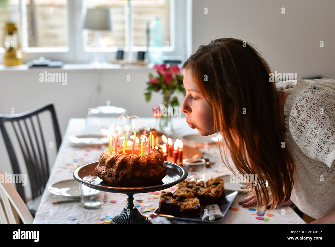 Ragazza adolescente soffiando le candeline sulla torta di compleanno a parte in Amburgo, Germania Foto Stock