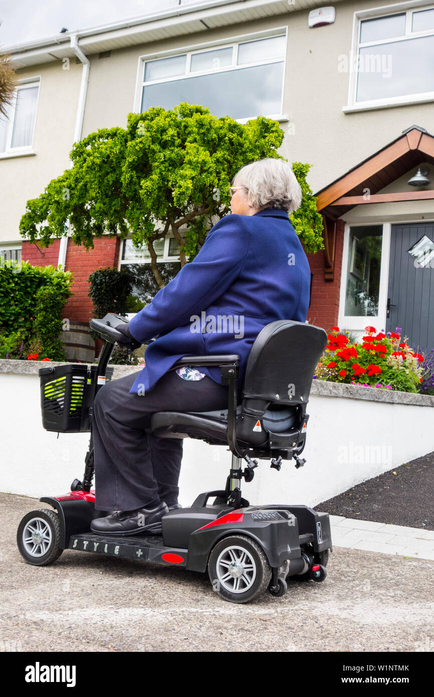Una donna più anziana che viaggiano su una mobilità scooter Foto Stock
