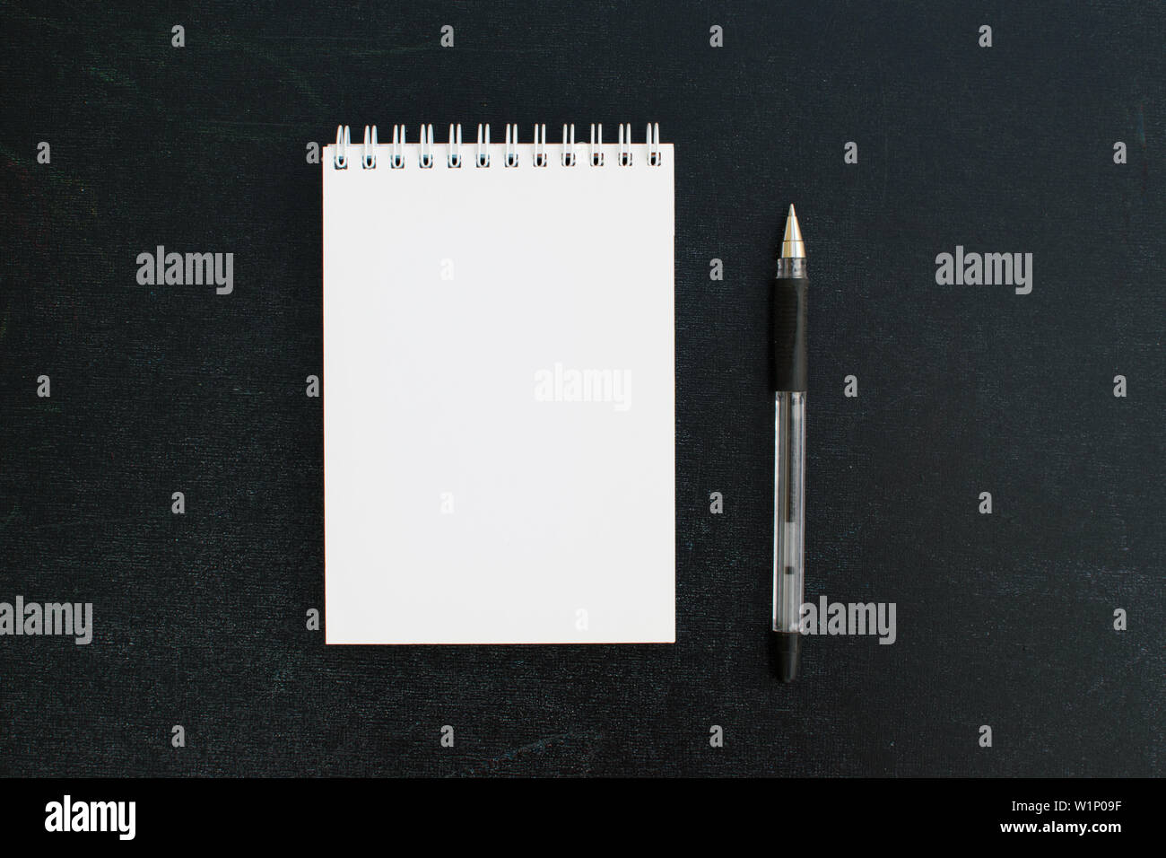 Aprire un vuoto di Blocco note sulla spirale su una scheda di colore nero lo sfondo con la penna nera. Foto Stock