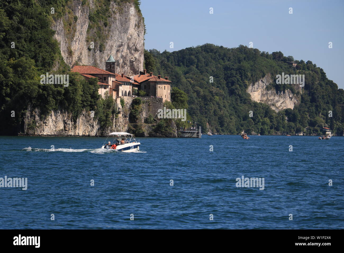 Il Lago Maggiore, Lombardia, Italia. circa giugno 2019. Eremo di Santa Caterina del Sasso si affaccia sul Lago Maggiore. Il motoscafo in primo piano. Foto Stock