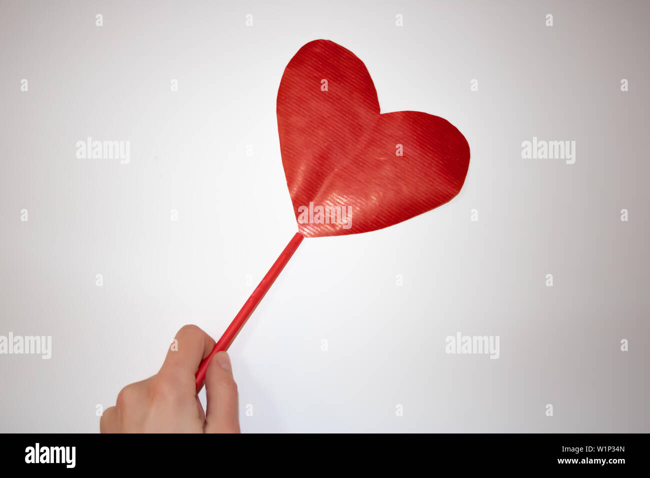 Donna mano che tiene una carta di colore rosso nel cuore per il giorno di san valentino Foto Stock