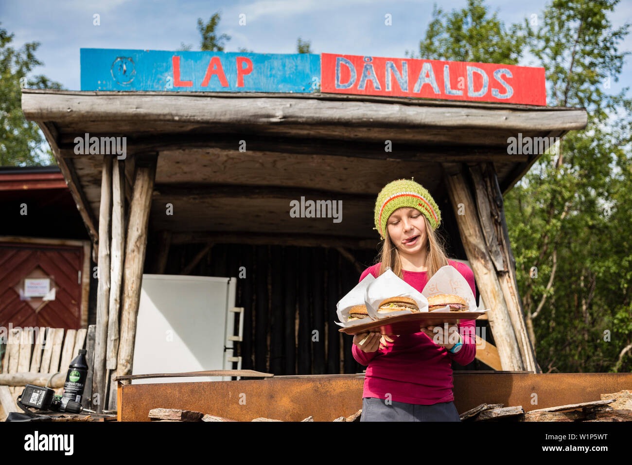 Una ragazza con hamburger con reindeermeat dal giro Danalds. A Ladtjojaure, Lapponia, Svezia. Foto Stock