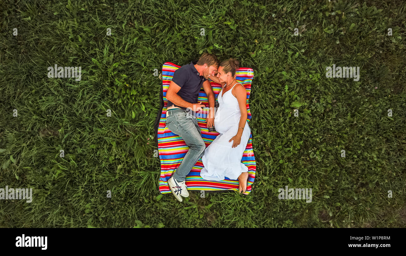Matura in amore durante la gravidanza su una coperta in prati Foto Stock