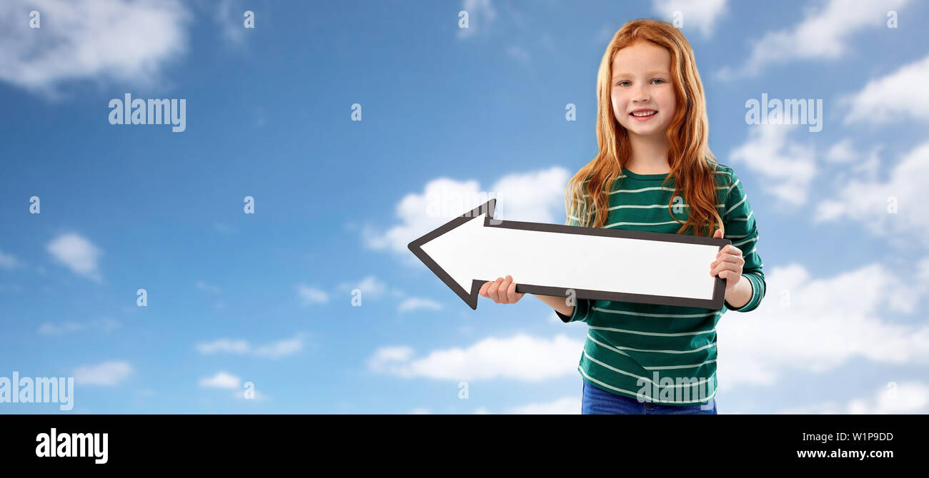 Sorridente dai capelli rossi ragazza con la freccia mostra a sinistra Foto Stock