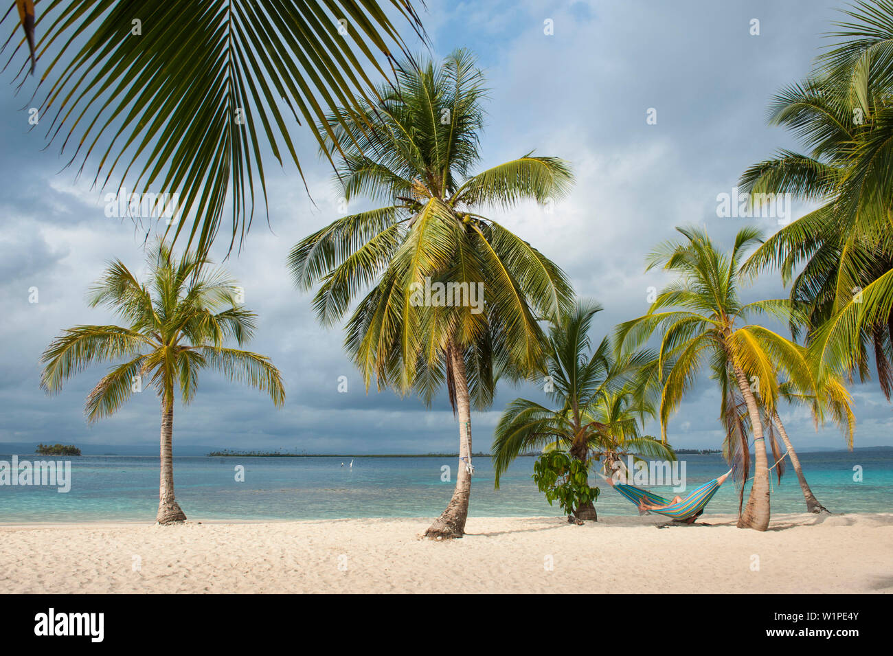 Un visitatore giornaliero da una spedizione nave da crociera si rilassa in una amaca appesa tra palme sulla spiaggia, isole San Blas, Panama, dei Caraibi Foto Stock