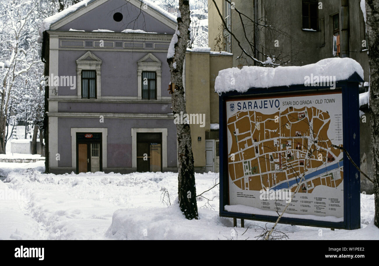 Il 28 marzo 1993 durante l'assedio di Sarajevo: in Hadziristica Street,vicino al fiume Miljacka, un grande segno mostra un piano urbanistico della città vecchia. In fondo è un JAT (compagnie aeree iugoslave) ufficio. Foto Stock