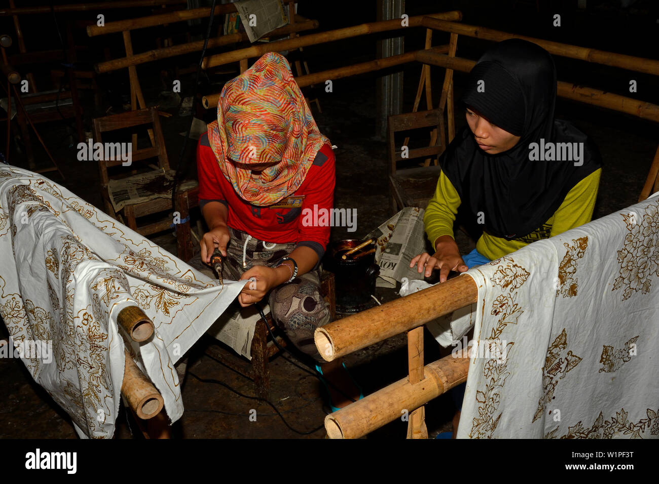 Yogyakarta, Indonesia - 2015.11.10: giovani donne applicando modelli in cera su tessuti in una fabbrica Batik Foto Stock