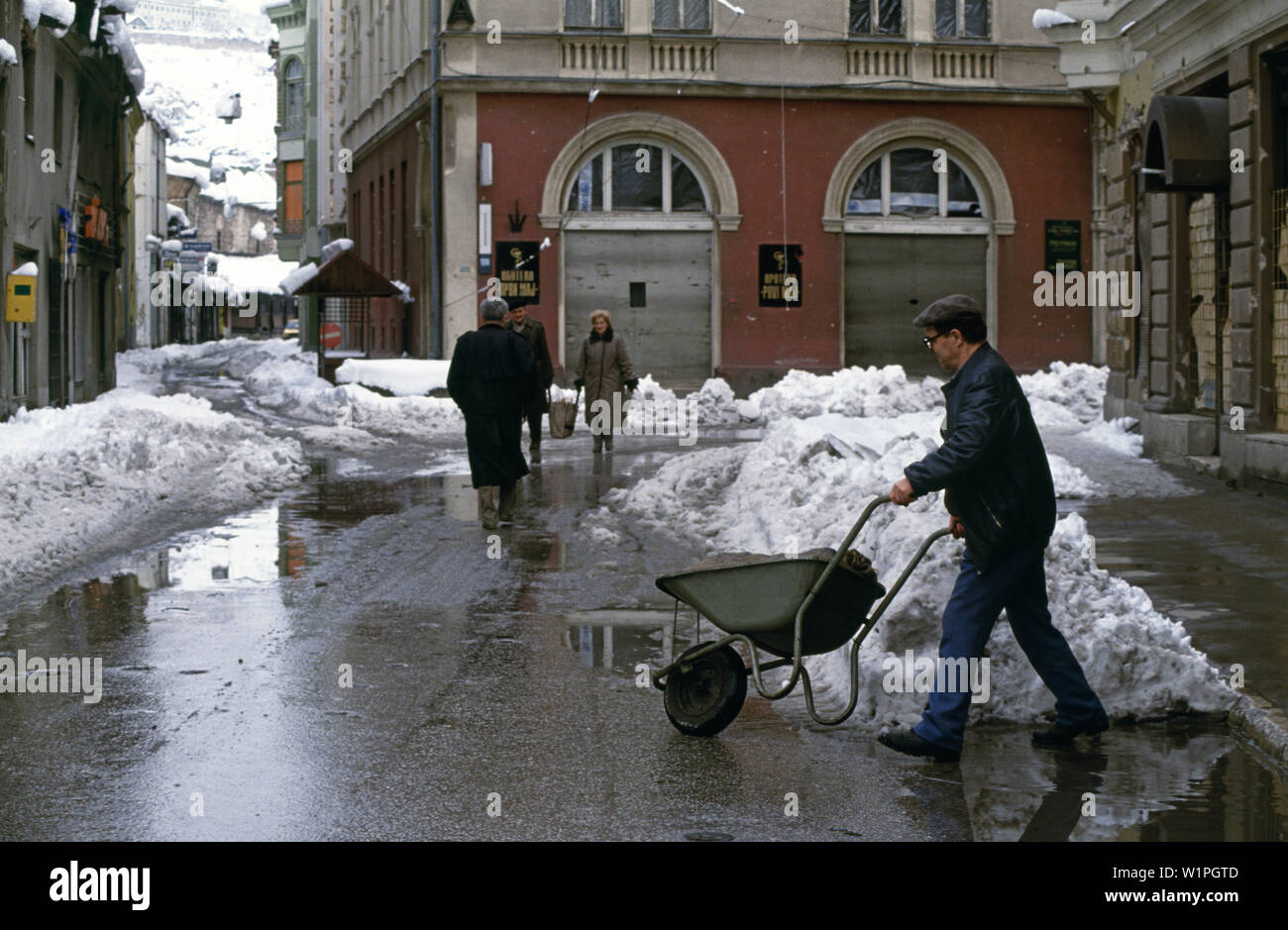 Il 28 marzo 1993 durante l'assedio di Sarajevo: un uomo spinge una carriola trasporta un sacco dell'UNHCR di granella essiccata o mais su Narodne Jugoslovenske Armije (rinominato Zelenih beretki Street dopo la guerra). Foto Stock