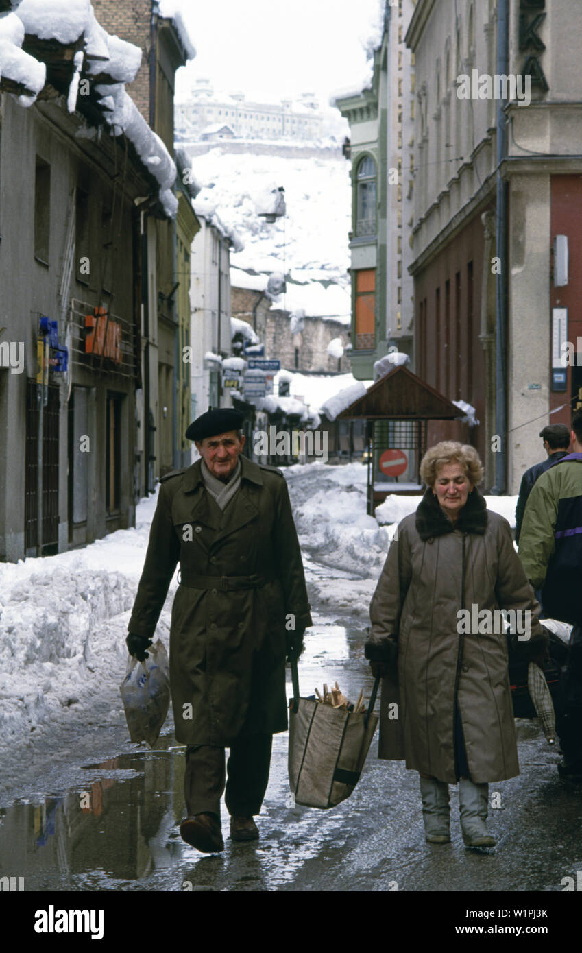 Il 28 marzo 1993 durante l'assedio di Sarajevo: un paio di condividere il carico di un sacco riempito con pezzi di legno su Narodne Jugoslovenske Armije (rinominato Zelenih beretki Street dopo la guerra). Foto Stock