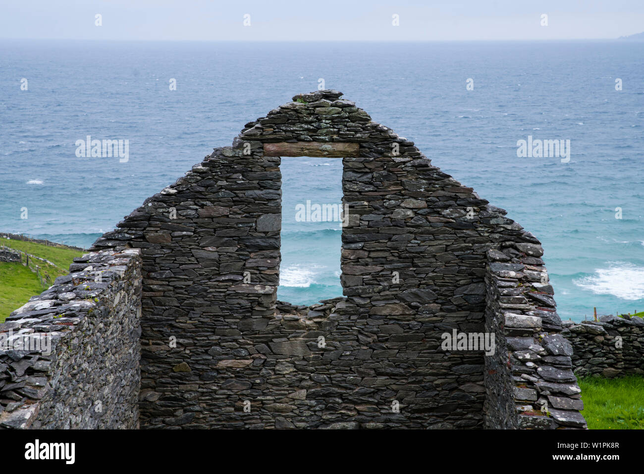 Le onde dell'Oceano Atlantico visto attraverso la finestra dei resti di un antico edificio di pietra senza un tetto visto da mentre si cammina per la strada di Dingle Foto Stock