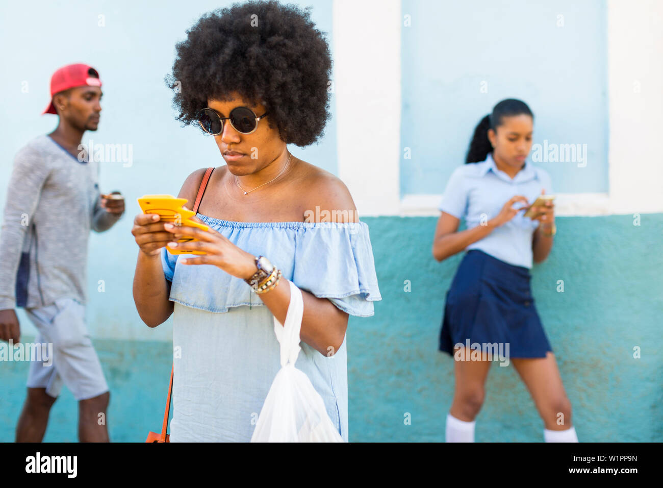 Giovani cool persone sul loro cellulare, prendendo un resto, uniformi scolastiche, famiglia viaggi a Cuba, congedo parentale, vacanze, time-out, avventura, Trinidad, provi Foto Stock