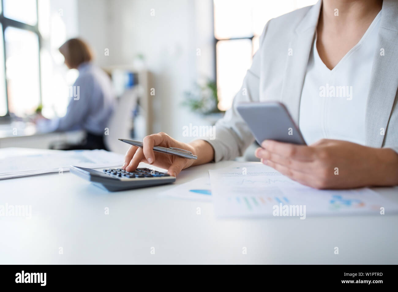Imprenditrice con la calcolatrice lavorando in ufficio Foto Stock