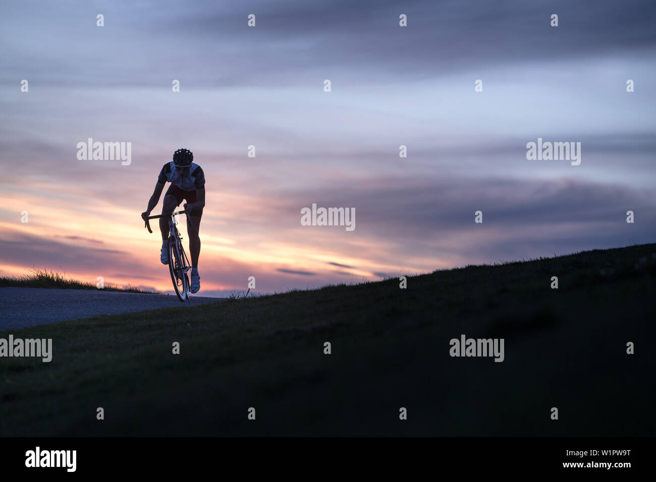 Giovane uomo sul suo ciclo racing mentre il tramonto alle Alpi Kitzbühler, Kitzbühlerhorn, Tirolo, Austria Foto Stock