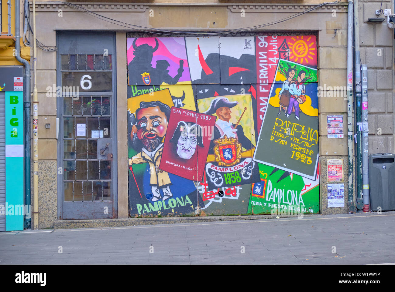 Edificio porta in Pamplona ornata con la riproduzione degli anni passati i manifesti pubblicitari per la San Fermin festival Foto Stock