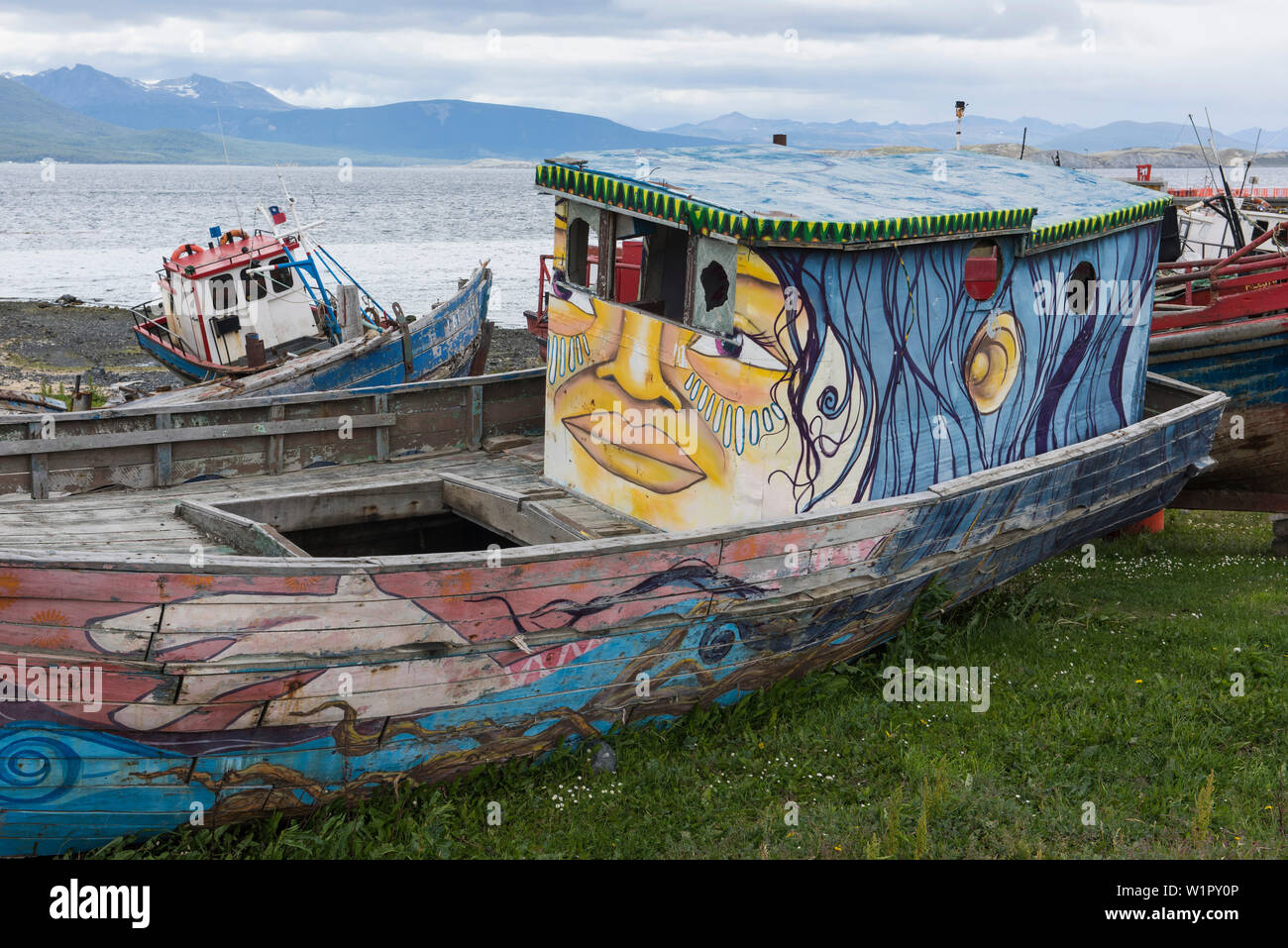 Dipinte in modo creativo spiaggiata barche giacciono sulla spiaggia vicino al porto di Puerto Williams, Magallanes y de la Antartica Chilena, Patagonia, Cile Foto Stock