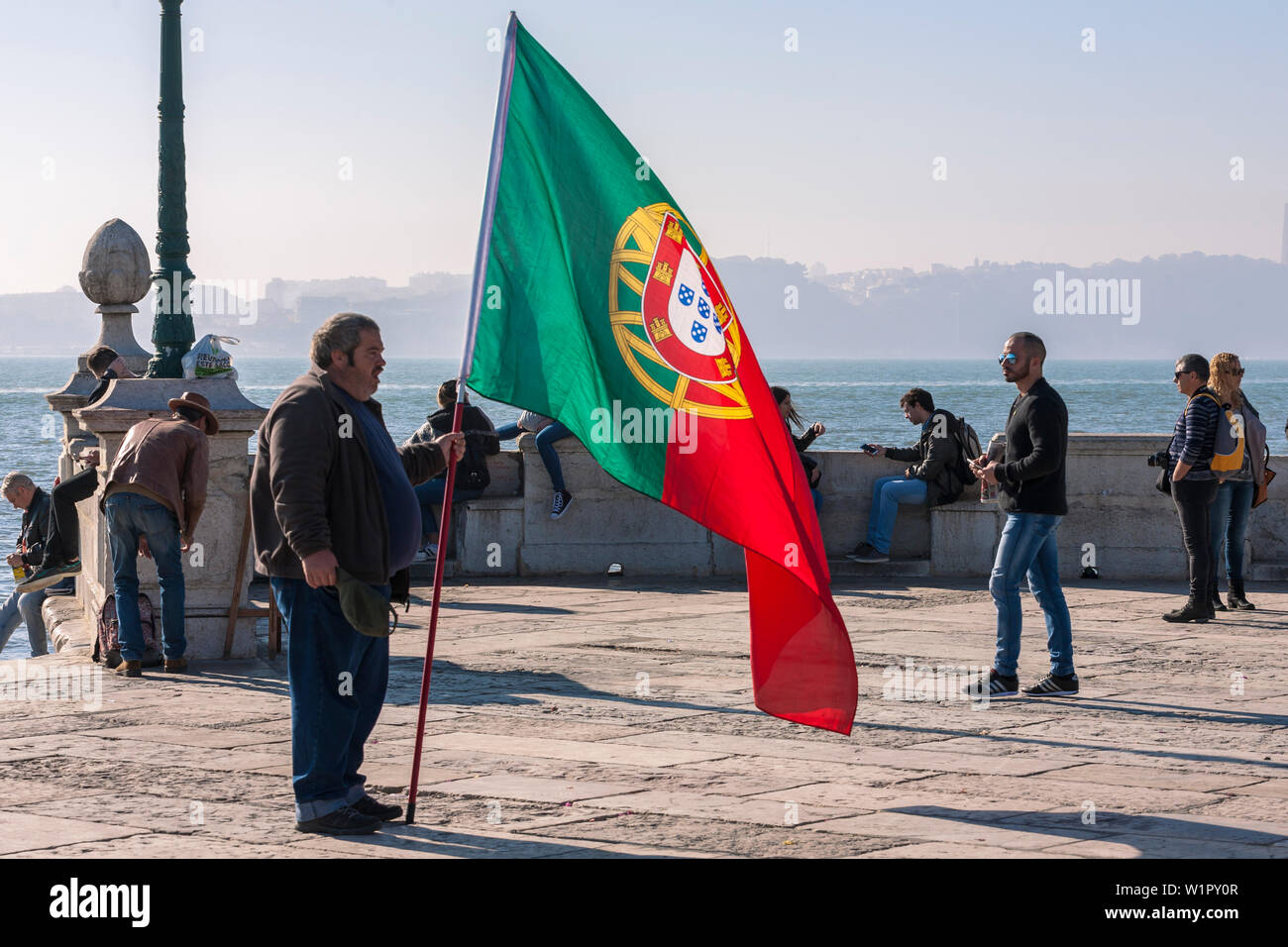 Grasso patriottica uomo con bandiera portoghese, Cais das Colunas, Praça do Comércio, Lisbona, Portogallo Foto Stock
