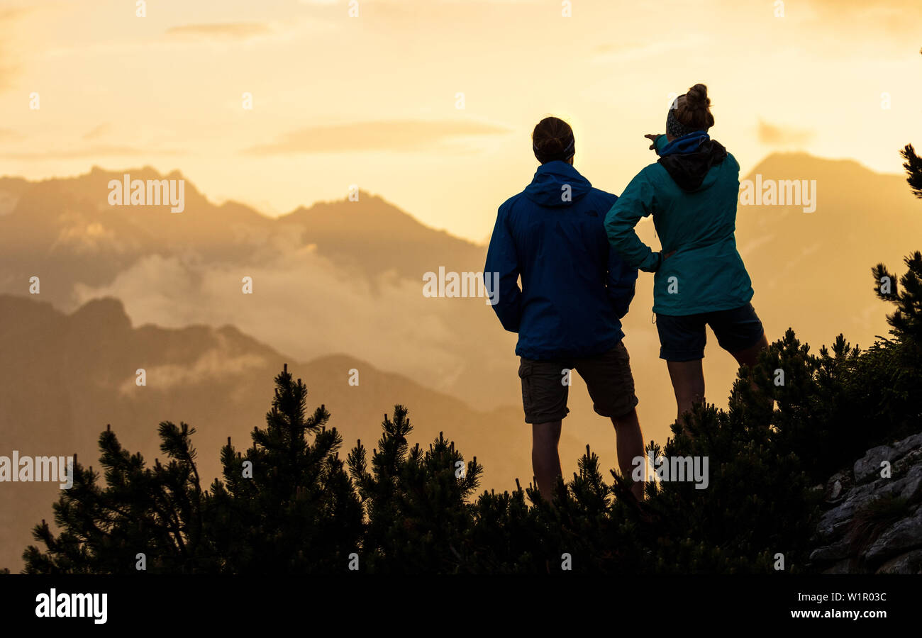Giovane donna e uomo guarda guardare il tramonto scenerie montagna, silhouette, Scharnitz, Tirol Österreich Foto Stock