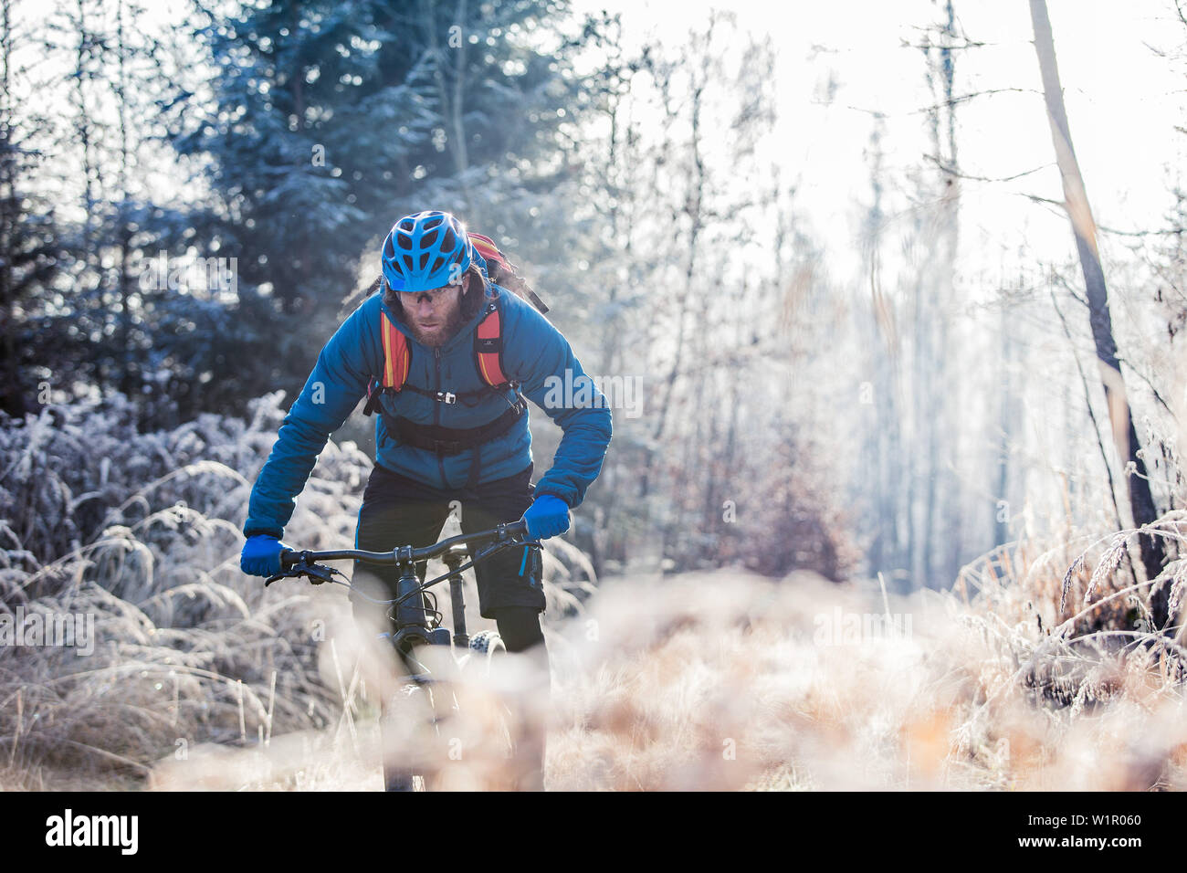 Giovane uomo a cavallo con la sua moto attraverso un con coperto di brina foresta, Allgaeu, Baviera, Germania Foto Stock