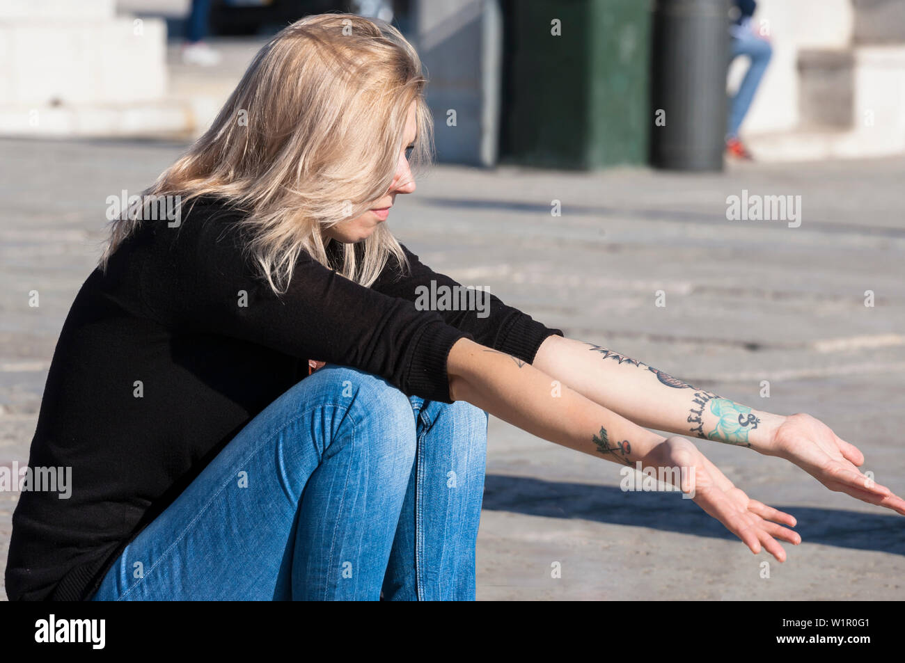 Una giovane donna gode del sole invernale a Cais das Colunas, Praça do Comércio, Lisbona, Portogallo Foto Stock