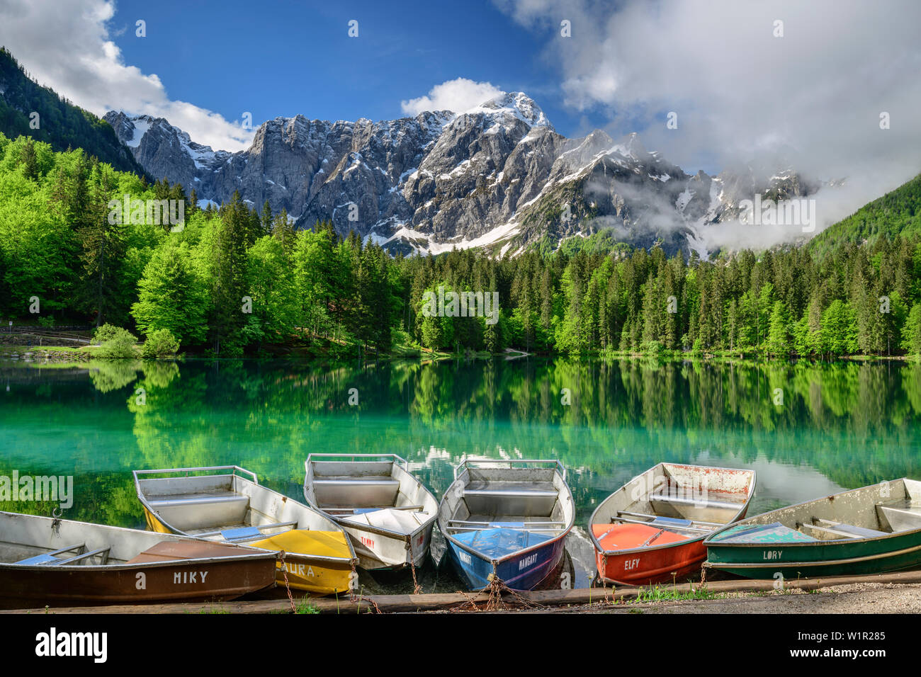 Barche colorate che stabilisce nel lago di Fusine, Mangart in background, Lago Fusine, sulle Alpi Giulie, Friuli, Italia Foto Stock