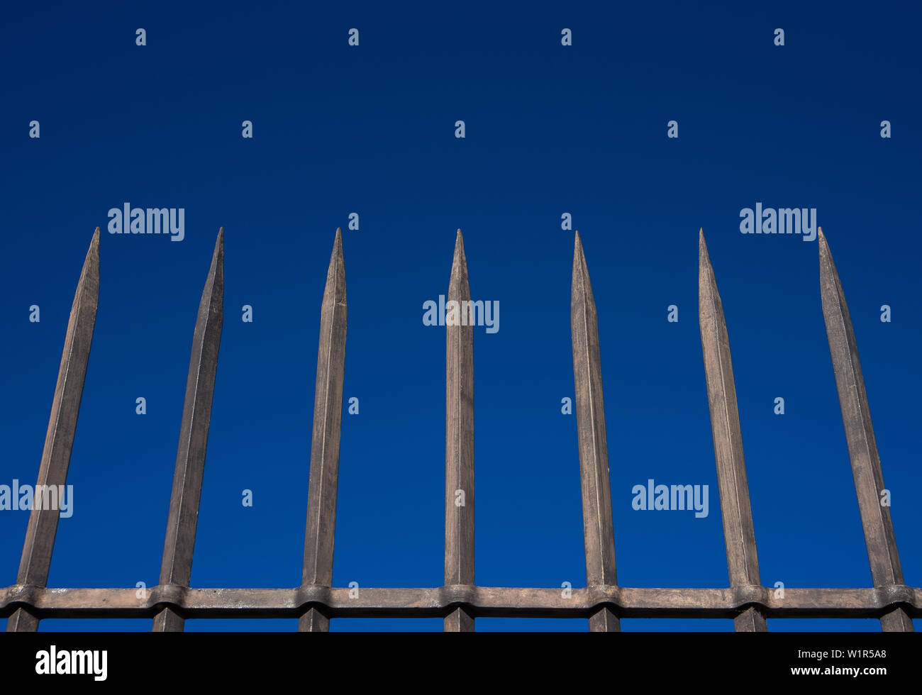 Recinzione in acciaio barriera con barre appuntite contro il cielo blu. Concetto di reclusione, ostacolo, sicurezza di protezione Foto Stock