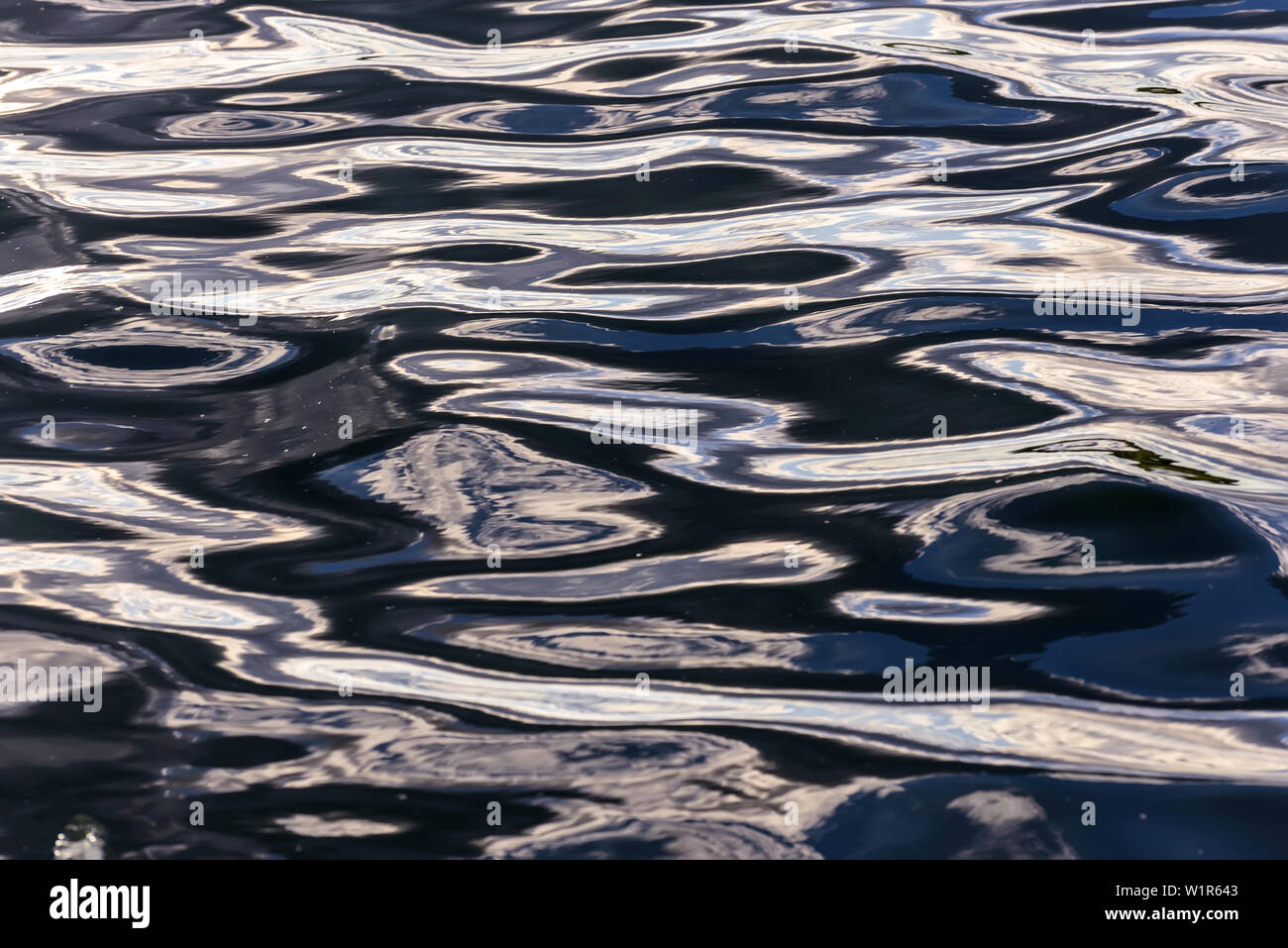 Abstract sfondo naturale di acqua texture con la riflessione di nuvole in onde bellissime dell' acqua scura al tramonto Foto Stock