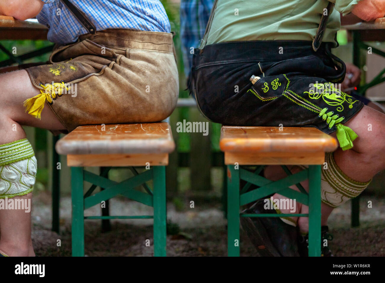 Due uomini in breve pantaloni di pelle sono il back-to-back sulle banche nel giardino della birra; vista in dettaglio Foto Stock