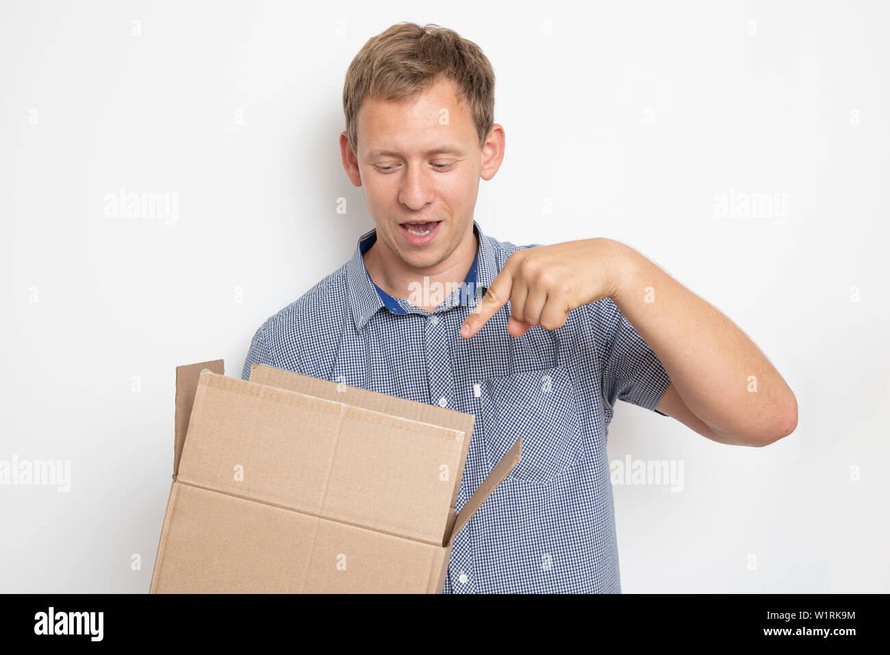 Descrizione: curioso uomo cerca all'interno di una scatola di cartone che egli tiene nelle sue mani su sfondo bianco Foto Stock