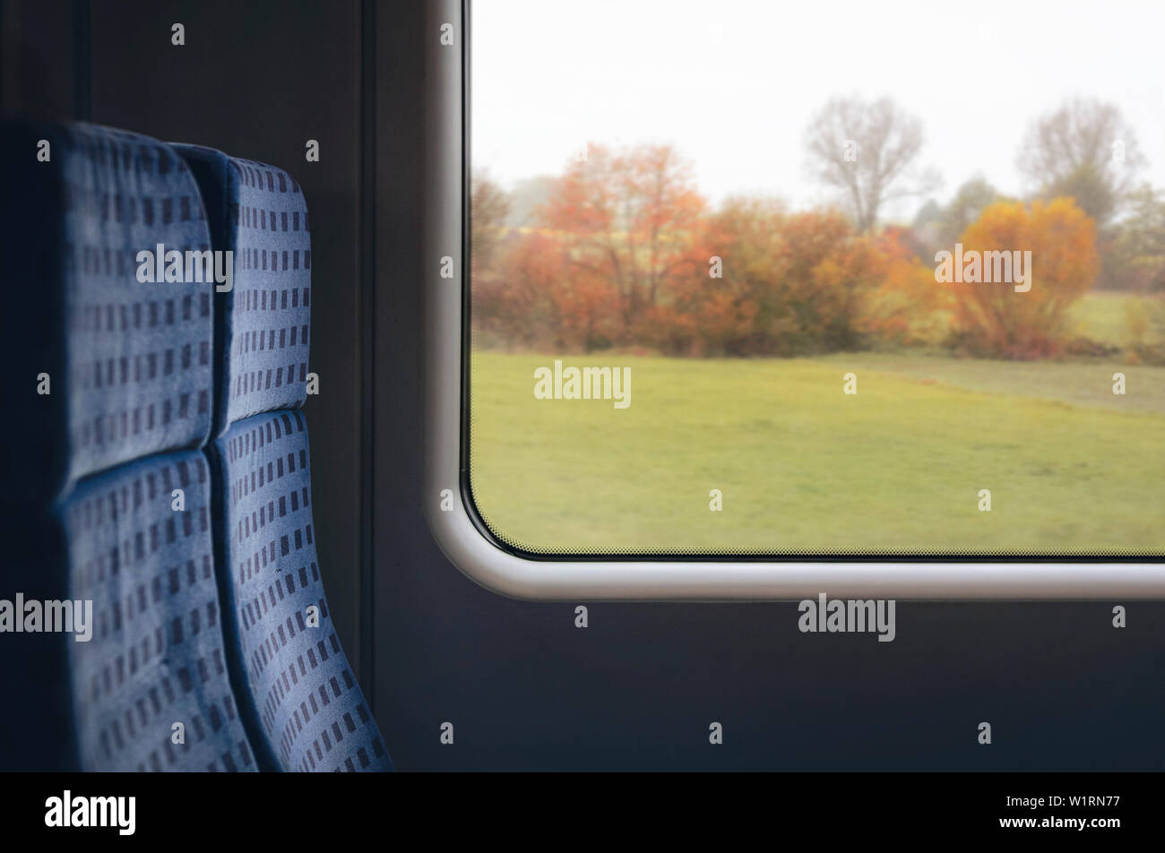 Close-up di treno interno con sedie blu e con una finestra a vista con un colorato autunno scena, viaggiando in Germania. Il tempo di viaggio immagine con copia spazio. Foto Stock