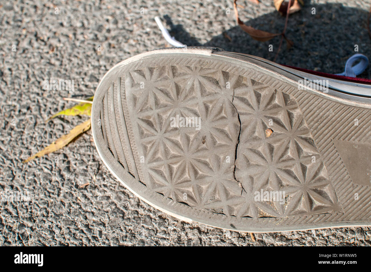 Una sneaker incrinato suola in gomma closeup su sfondo di asfalto Foto Stock