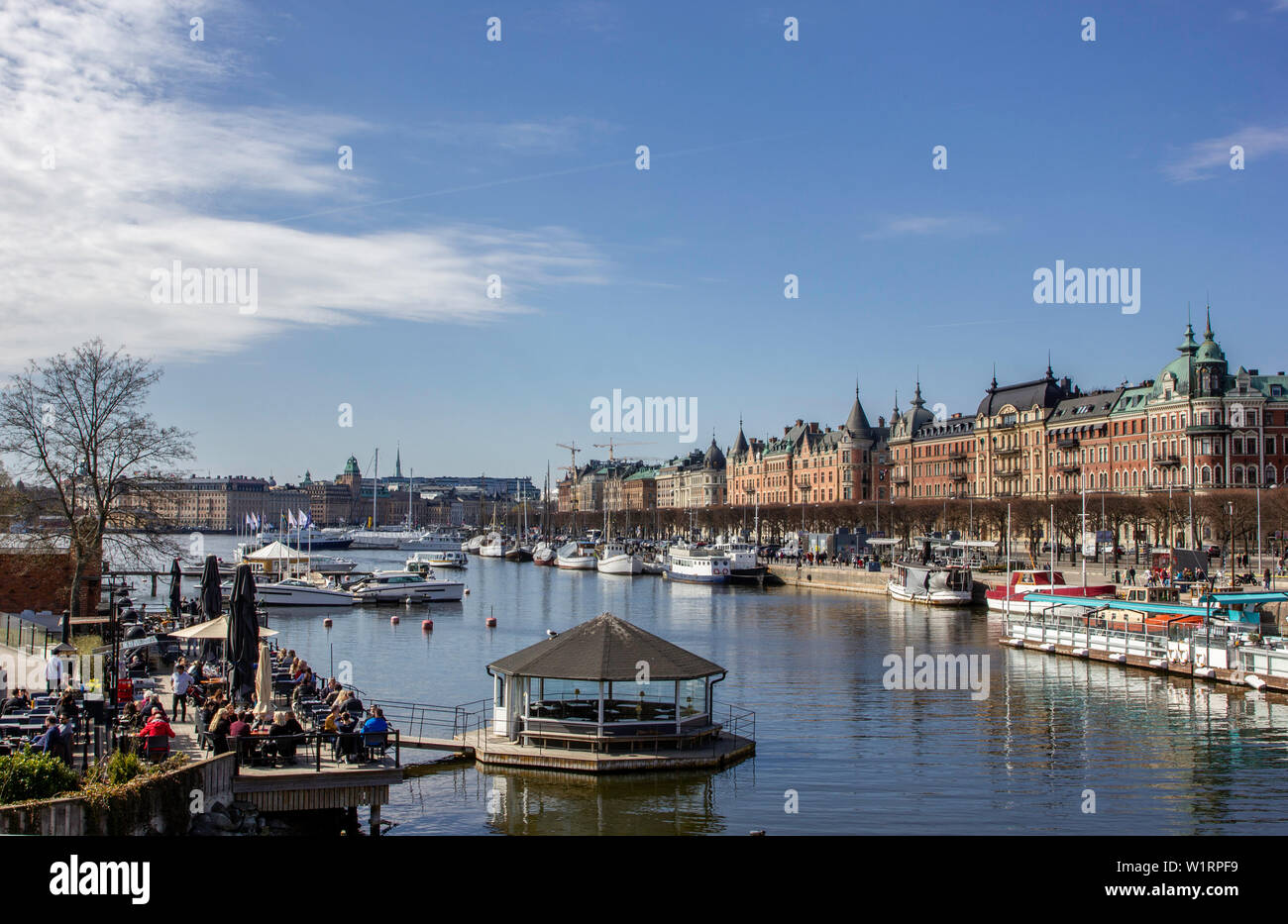 Molte persone sedute e cenare in ristoranti esterni che la linea i numerosi corsi d'acqua di Stoccolma in Svezia su una bella giornata di primavera. Foto Stock